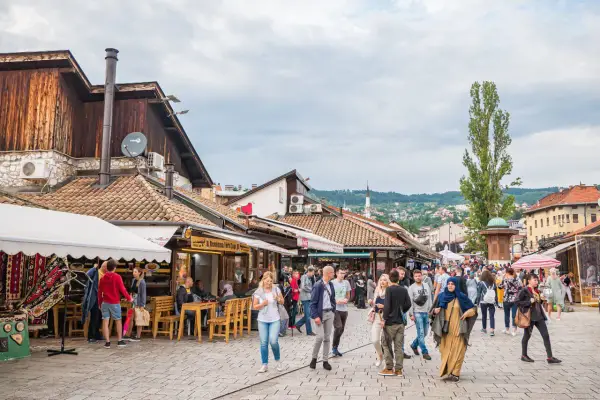 Tętniący życiem bazar w Bośni i Hercegowinie, z ludźmi spacerującymi między straganami i kawiarniami.
