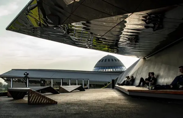 Nowoczesna architektura i ludzie odpoczywający pod zadaszeniem. W tle kopuła Muzeum Śląskiego, jedna z głównych katowice atrakcje.