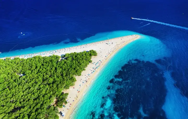 Widok z lotu ptaka na słynne chorwackie plaże Zlatni Rat. Turkusowa woda, biały piasek i zielony las tworzą rajski krajobraz.